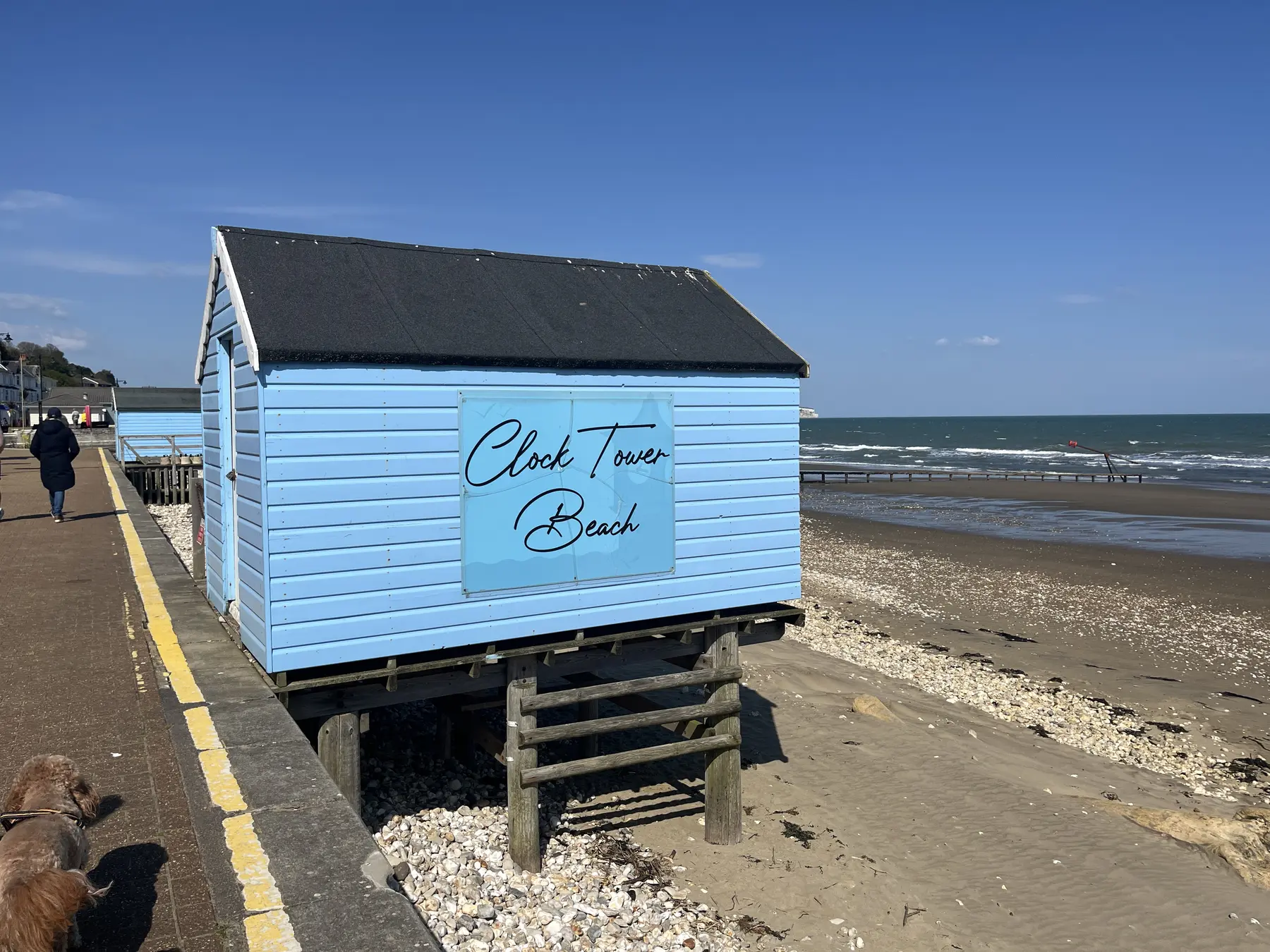 A blue beach hut beside the sandy shoreline