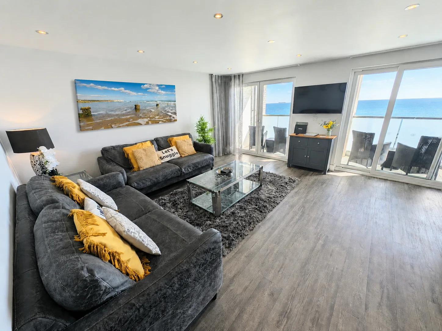 The bright apartment lounge with its Sandown Bay board print, balcony and sea view