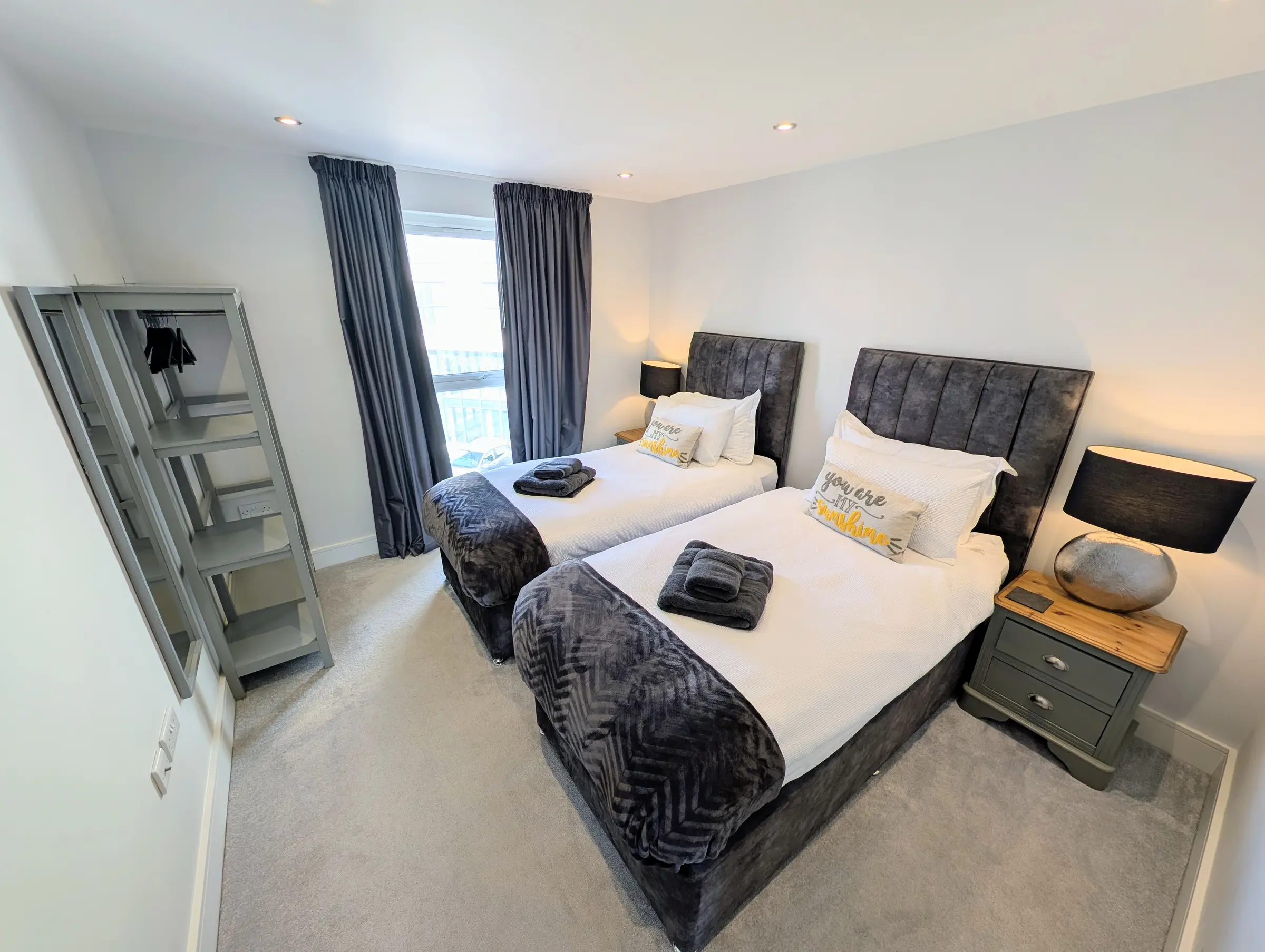 Twin bedroom with two full-size single beds, bedside lighting and hanging space